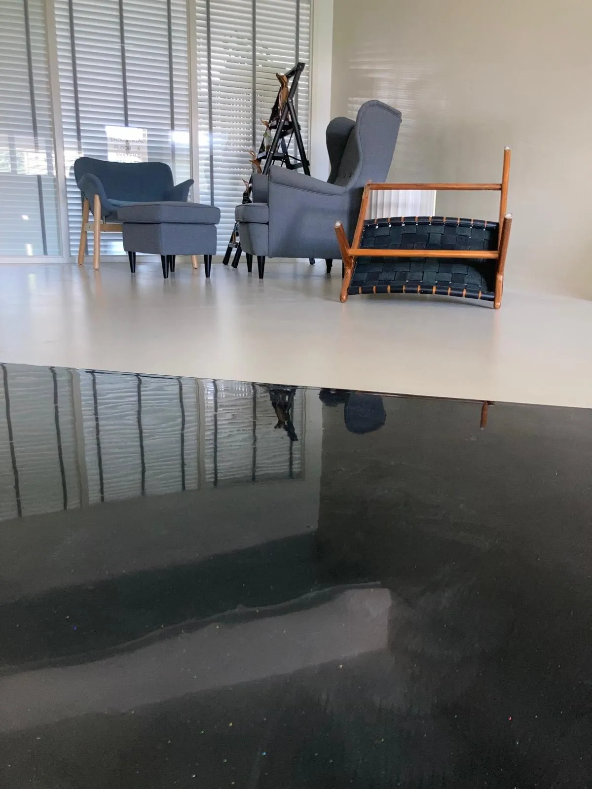Glossy dark IFS metallic epoxy floor reflecting armchairs in a living room