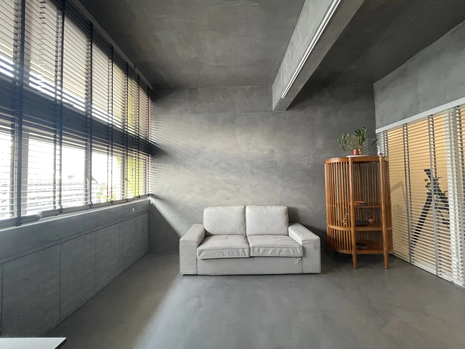 Seamless grey IFS MicroCrete microcement on the walls and floor of a living room with a white sofa