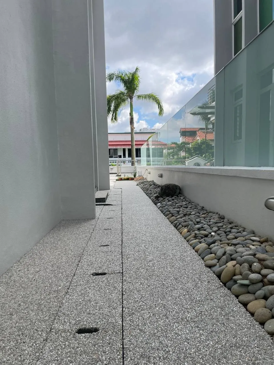 IFS stone carpet path along the side of a house, beside a bed of river pebbles